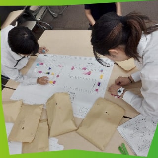 大きな紙に切り貼りして何かを作っている様子